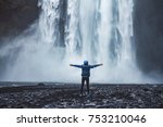 A person admirnig the beauty of Skogafoss waterfall located in Iceland