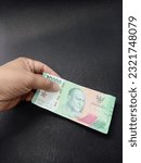 Small photo of a person holding a twenty thousand rupiah banknote with his left hand the latest issuance from Bank Indonesia ￼