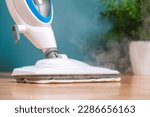 Small photo of man washes floors with steam mop. Floor treatment with hot steam. Hygienic control of cleanliness.