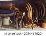 Small photo of A set of dishes and kitchen utensils. Cutting board. Dishes on the shelf. Kitchen utensils on the shelf. Plates with cutlery. A kitchen cabinet with dishes and utensils for the whole family is neatly