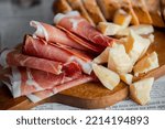 Small photo of Wooden board with cheese and ham. Board with jamon and cheese. Aperitif on the board. Jamon with bruschetta and parmesan.Delicious appetizer for wine.Italian appetizer. Jamon and salami with cheese.