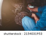Small photo of man changes a wheel hub with a wheel bearing in a car, Car disk brake pad replacement service by hand of mechanic man in car garage with flare light effect and copy space