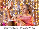 Small photo of Senior woman looking through sieve during Karva Chauth ceremony
