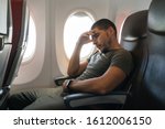 Small photo of man sleeps in an airplane while sitting in an armchair leaning on his arm. Inconvenient and uncomfortable sleep in the economy class.