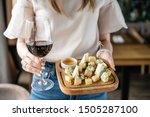 Girl holding glass red wine and wooden plate with cheese. Delicious cheese mix with walnuts, honey. Tasting dish on a wooden plate. Food for wine.