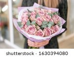 Beautiful bouquet of pastel purple roses in womans hands. the work of the florist at a flower shop. Delivery fresh cut flower. European floral shop.