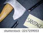 Small photo of Sabotage word written on paper note and chopped electrical cable, axe. Sabotage concept.