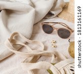 Small photo of Neutral fashion composition with women's accessories and bijouterie on beige blanket. String bag, straw hat, sunglasses, rings, earrings, pear. Minimal lifestyle concept.