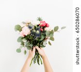 Small photo of Beautiful flowers bouquet in girls hands: bombastic roses, blue eringium, eucalyptus, isolated on white background. Flat lay, top view. Floral composition