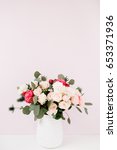 Small photo of Beautiful flowers bouquet: bombastic roses, blue eringium, eucalyptus branches in flowerpot at pale pastel pink wall. Floral lifestyle composition.