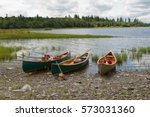 Three Canoes On A Lake's Rocky...