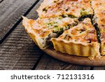 Quiche Lorraine with chicken and vegetables on rustic dark table background. Pie with mushrooms, chicken and broccoli on wooden kitchen board. Traditional French food. Closeup, copy space