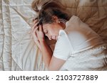 Top view depressed lonely upset caucasian adult woman lying on bed in bedroom. Portrait of middle-aged woman in crisis and with psychological problems. Mental health, melancholy, loneliness concept.