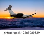 Modern private jet flying in the sunrise sky