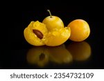 Small photo of Yellow and ripe mirabelle plums placed on top of a black table