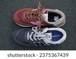 Small photo of Vilnius, Lithuania - September 12th 2023 - New Balance sports shoes, running shoes, sneakers, trainers, new, out of the box, one shoe red, one shoe black, warm, women, on the black outdoor rubber - 3