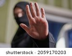 Small photo of A Muslim woman in traditional black clothing nikab showing stop hand gesture. Role of women in Islamic world. Domestic violence, discrimination of Muslim women. Stop domestic violence against women