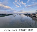 Small photo of A flowing river of Bangladesh. Where water is taken, the sky is filled with the white and yellow hues of the soft evening. Many boats ply in this river. The banks of the river are full of green trees
