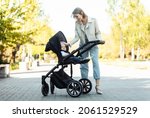 Portrait of a caring mother with her little daughter in stroller in park