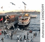 Small photo of Istanbul, Karakoy, Turkey - 15 October 2020: A passenger ferry at the pier, seagulls flying, people walking around, half of a smaller boat behind, historical Istanbul in the background, Turkish flag