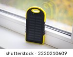 A yellow power bank with a solar battery during the day