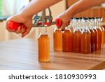 Small photo of Man using hand capper for brewing, with brown bottles of homemade liquor or alcohol. Selective focus.
