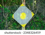 Small photo of Yellow shooting target is full of paintball paint splash with green leaf background