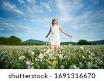 Woman in a field with flowers. Beautiful girl in a field with daisies.