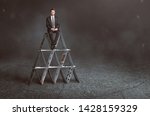 Small photo of Businessman is sitting on house of cards