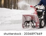 A man with a red snow-covered snow blower clears the area from snow. Clearing the area from snowfall.