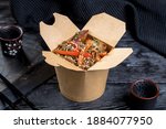 paper box with buckwheat noodle wok and grilled chicken fillet. decor on a black background.
