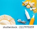 Small photo of Beach sand and seashells with straw hat and bottles od sunscreen