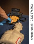 Small photo of First aid training – The resusitation has started. The instructor ist going to activate the shock. The shock discharge button flashes red. The AED is loaded and the patient is now being shocked.