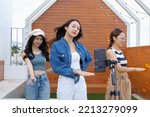 Young Asian woman with her friend tiktoker created her dancing video by smartphone camera together on rooftop outdoor at sunset. To share video to social media application