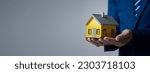 Small photo of Person puts her hand on top of a miniature house model, photo of home insurance concept, when buying a new home should have home insurance to be sure if there is any danger to the home.