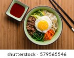 Top view of Bibimbap, a classic Korean meal. Rice is topped with seasoned vegetables, meat and a sunny side up fried egg on top. Spicy chili sauce can be added to finish off this savoury Asian dish.