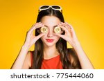 young beautiful girl holds golden bitcoins in hands and closes their eyes, on a yellow background