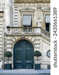 Small photo of Paris ancient stone building with wooden carved double doors, stone staircase, French windows with awning canvas blinds, statue, rich stucco fretwork and potted plants