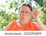 Small photo of woman 50-55 years old looks into distance, sees poorly, displeasure on face, regular eye checkups for maintaining visual health, condemnation snob