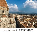 The dome of Santa Maria del Fiore and the scaffolding on top of the chevet's dome. Beside the cathedral is a bird's eye view of Florence, Italy and the hills beyond.