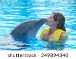 Happy Woman Kissing Dolphin In...