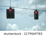 Bright red stop traffic lights high above street on blue sky background