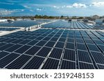 Small photo of Aerial view of blue photovoltaic solar panels mounted on industrial building roof for producing clean ecological electricity. Production of renewable energy concept