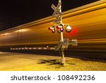 railroad crossing with passing train by night