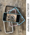 Small photo of Transparent mobile phone cases on a wooden background, light blue case, pink case, black case and white case