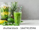 Blender with fresh ingredients to making healthy detox smoothie with glass of green prepared drink with a straw. Vegan cooking concept