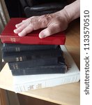 Small photo of A hand is placed on top of a stack of bibles, ready to swear the truth