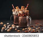 Small photo of Close up view of two freakshake in mason jar on brown table. Freaked milkshake with chocolate, pretzel, marshmallow, popcorn and waffles. Trendy food concept - freak shake