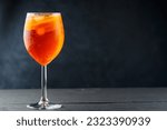 Aperol Spritz cocktail in glass with fresh orange on dark wooden boards. Glass of Aperol Spritz cocktail served in a wine glass. Copy space