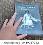 Small photo of Bogor, Indonesia - January 20, 2024: Hand holding Helen Keller's book "The Story of My Life"